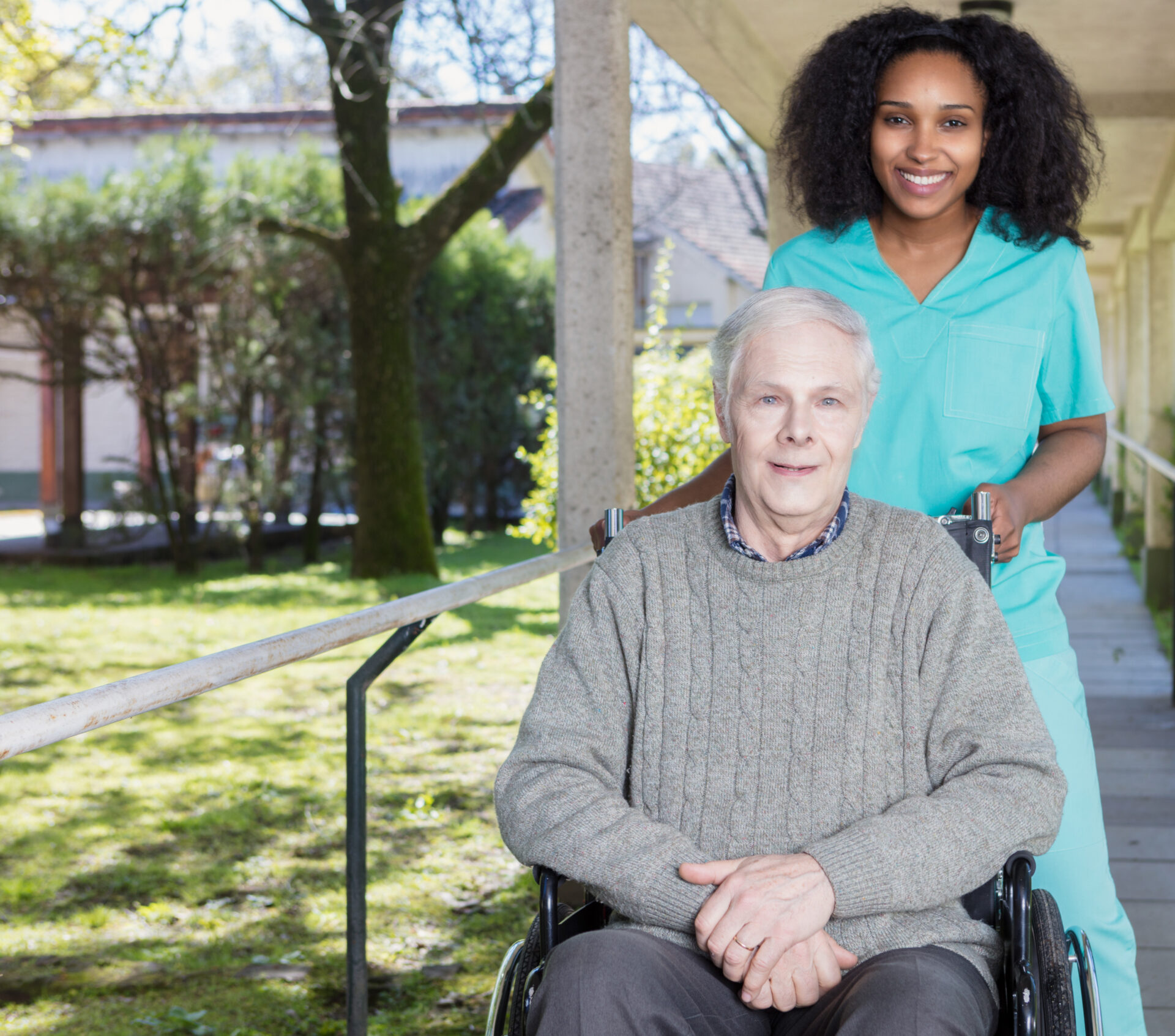 A woman standing next to an older man in a wheelchair.